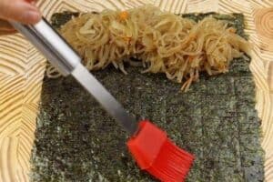 Brush some water on the edge of nori sheet before rolling