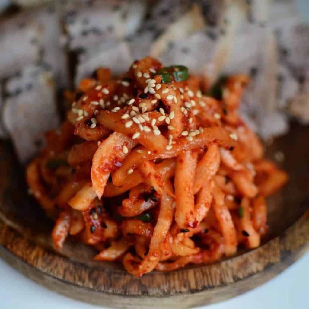Moochae Musaengchae Radish kimchi with sesame seeds on wooden platter