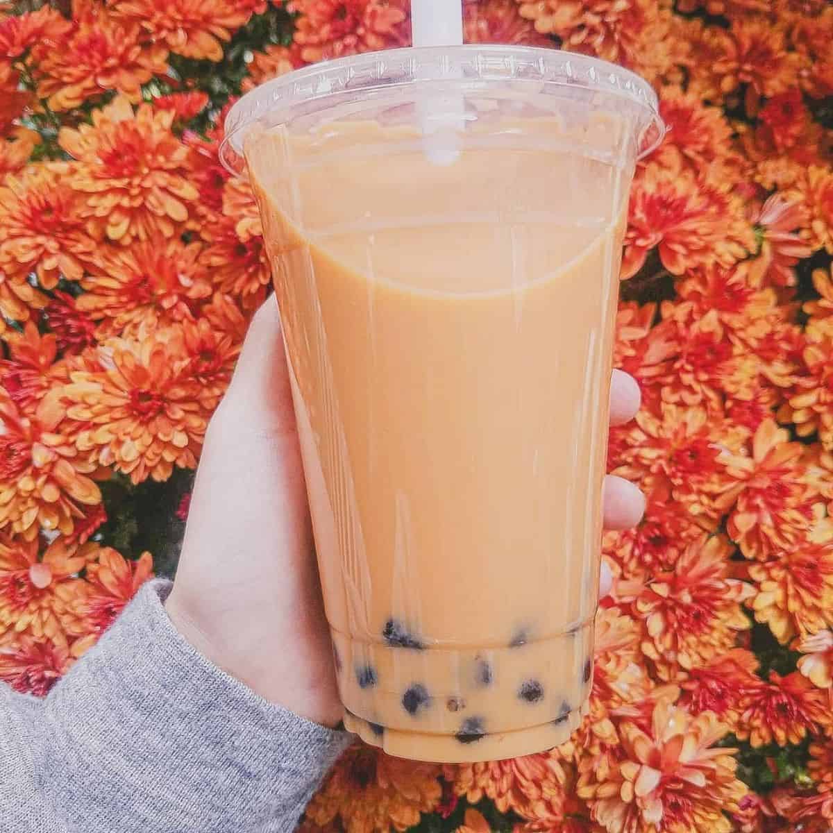 Boba drink with tapioca pearls with flowers in the background