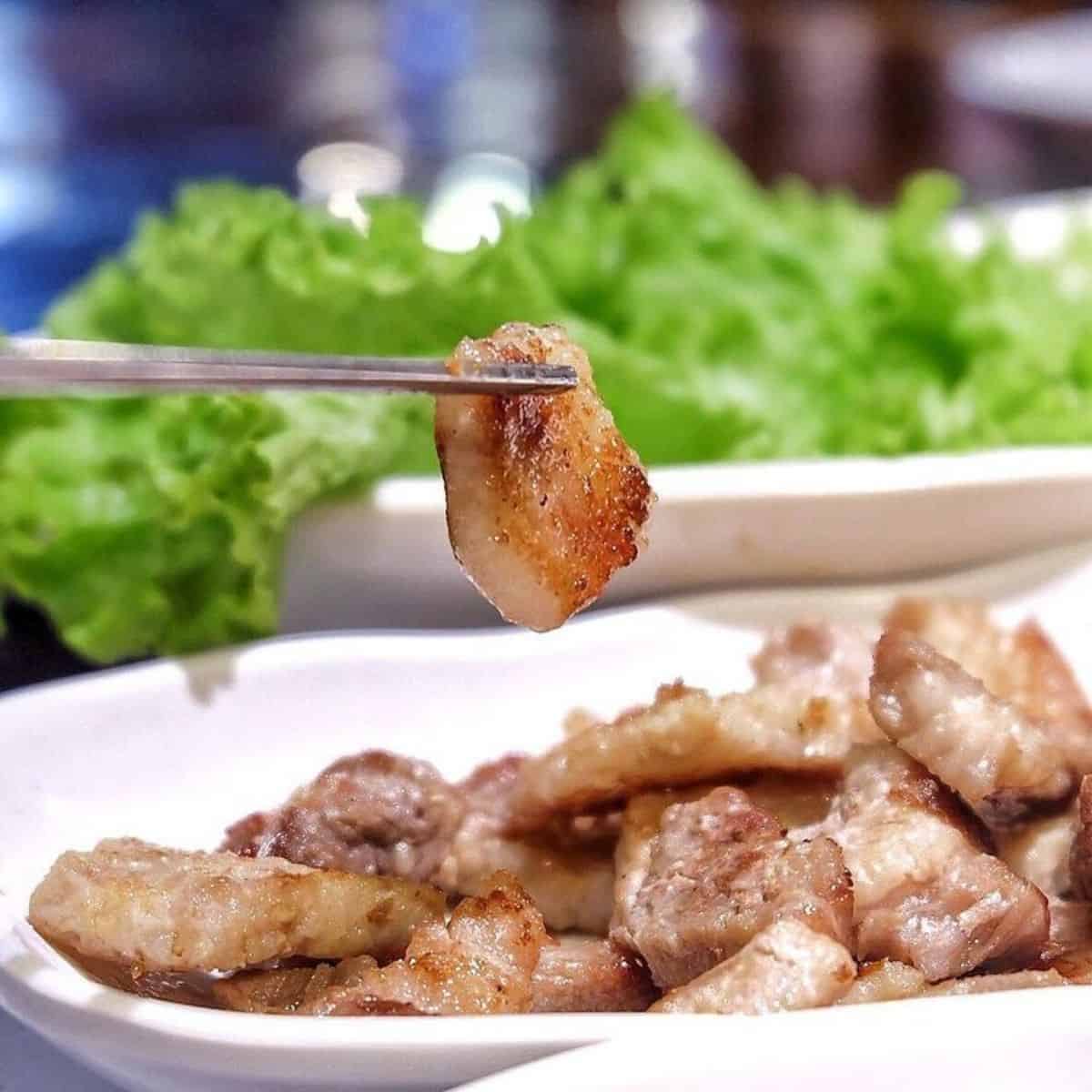 Piece of pork belly with metal chopstick