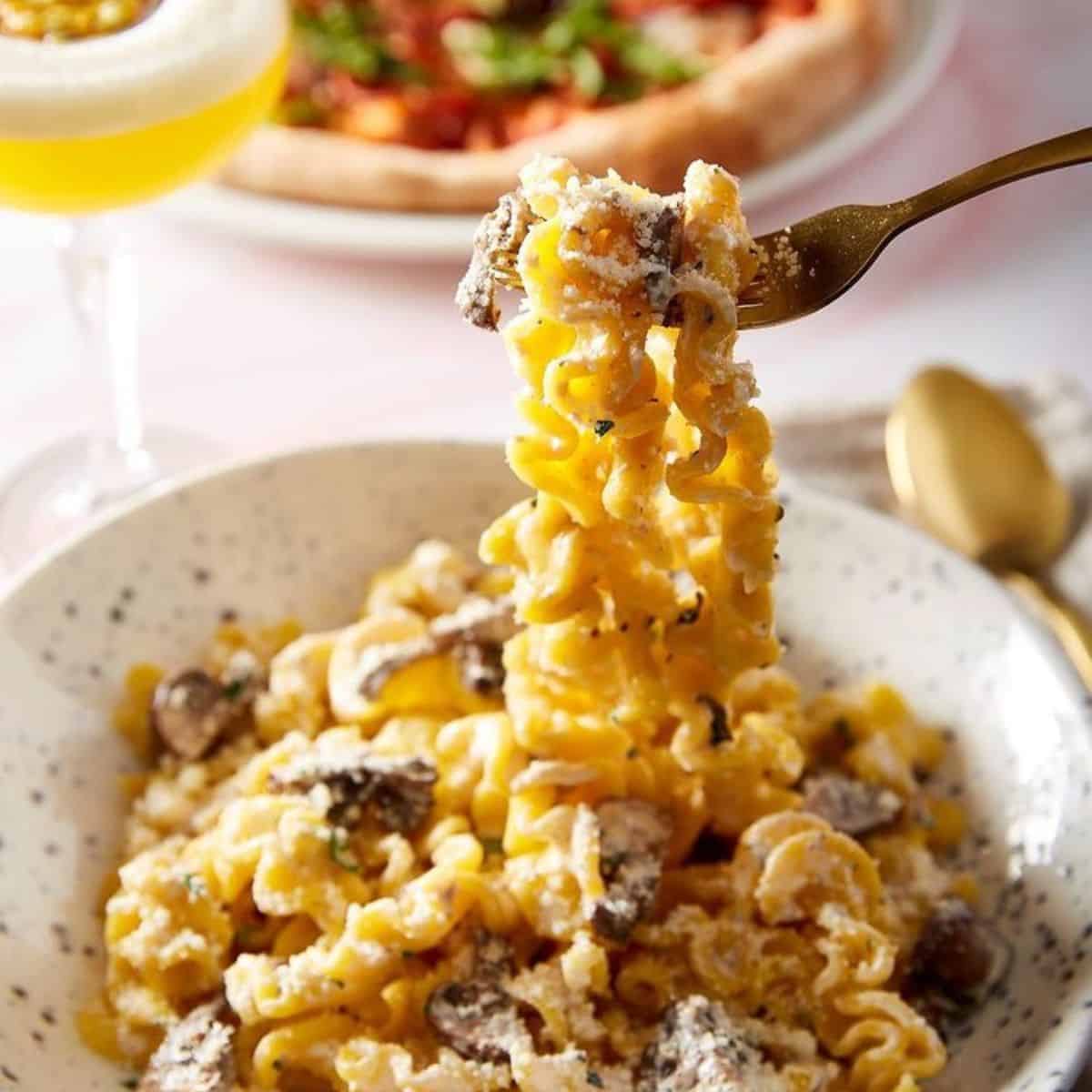 a portion of cheesy pasta with cocktail on side Bella Italia