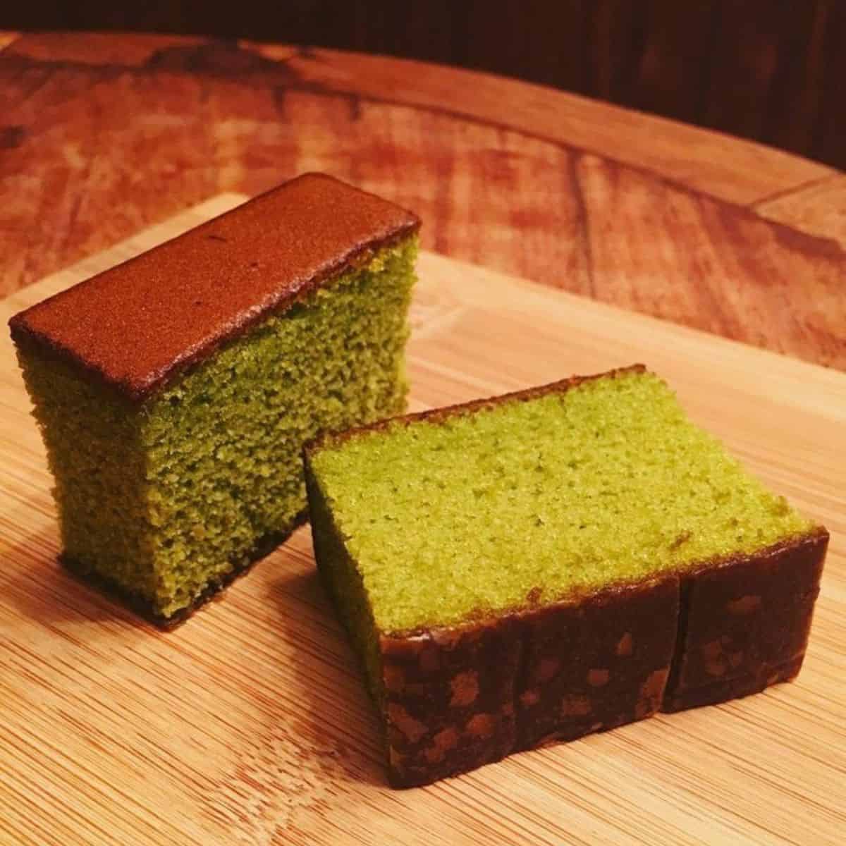 2 slices of matcha cake on a wood board