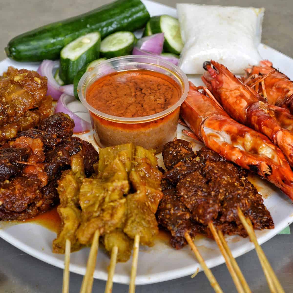 Alhambra Heritage & Original Satay Club Prawn satay and different skewers with chili dip in the middle and sliced cucumber on the side