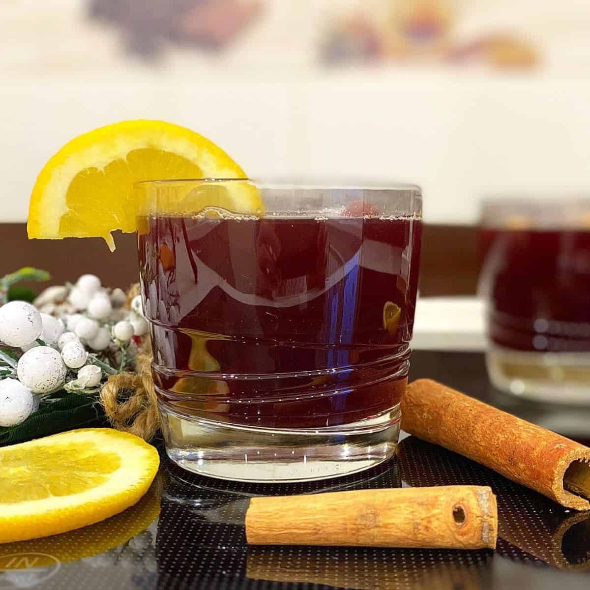 Non-alcoholic mulled wine in a small cup with lemon on side and cinnamon stick