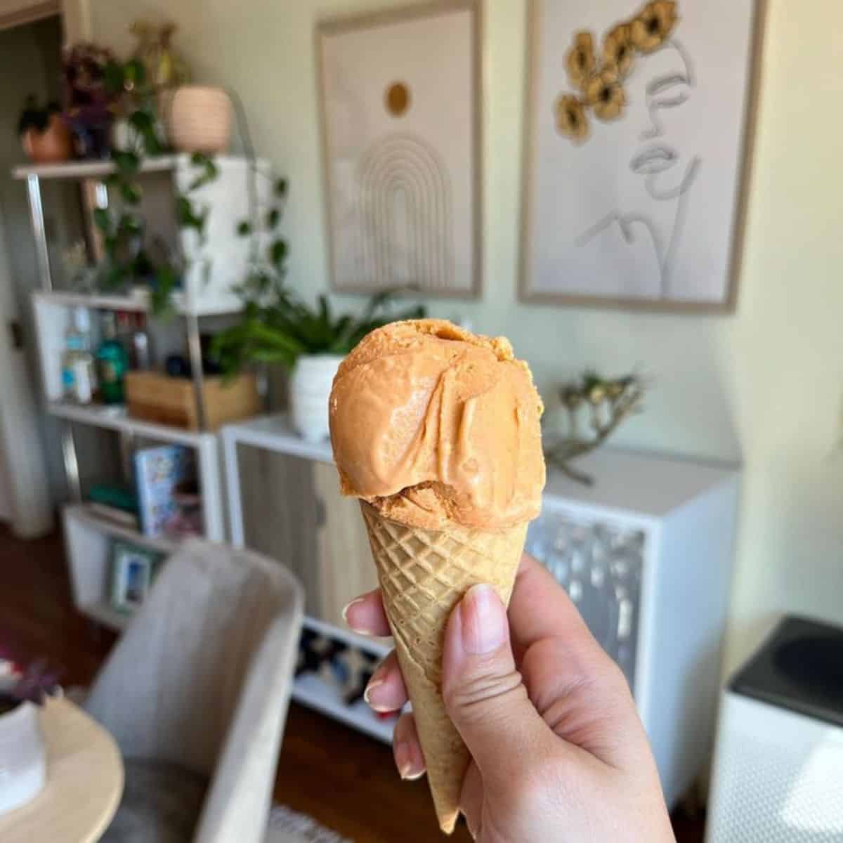 One scoop of thai tea ice cream on a brown waffle cone