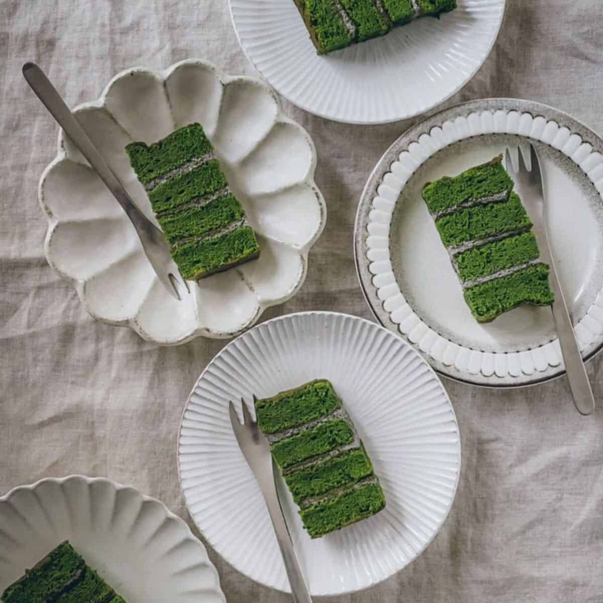 slices of matcha sponge cake on a white plate with black sesame cream in between layers