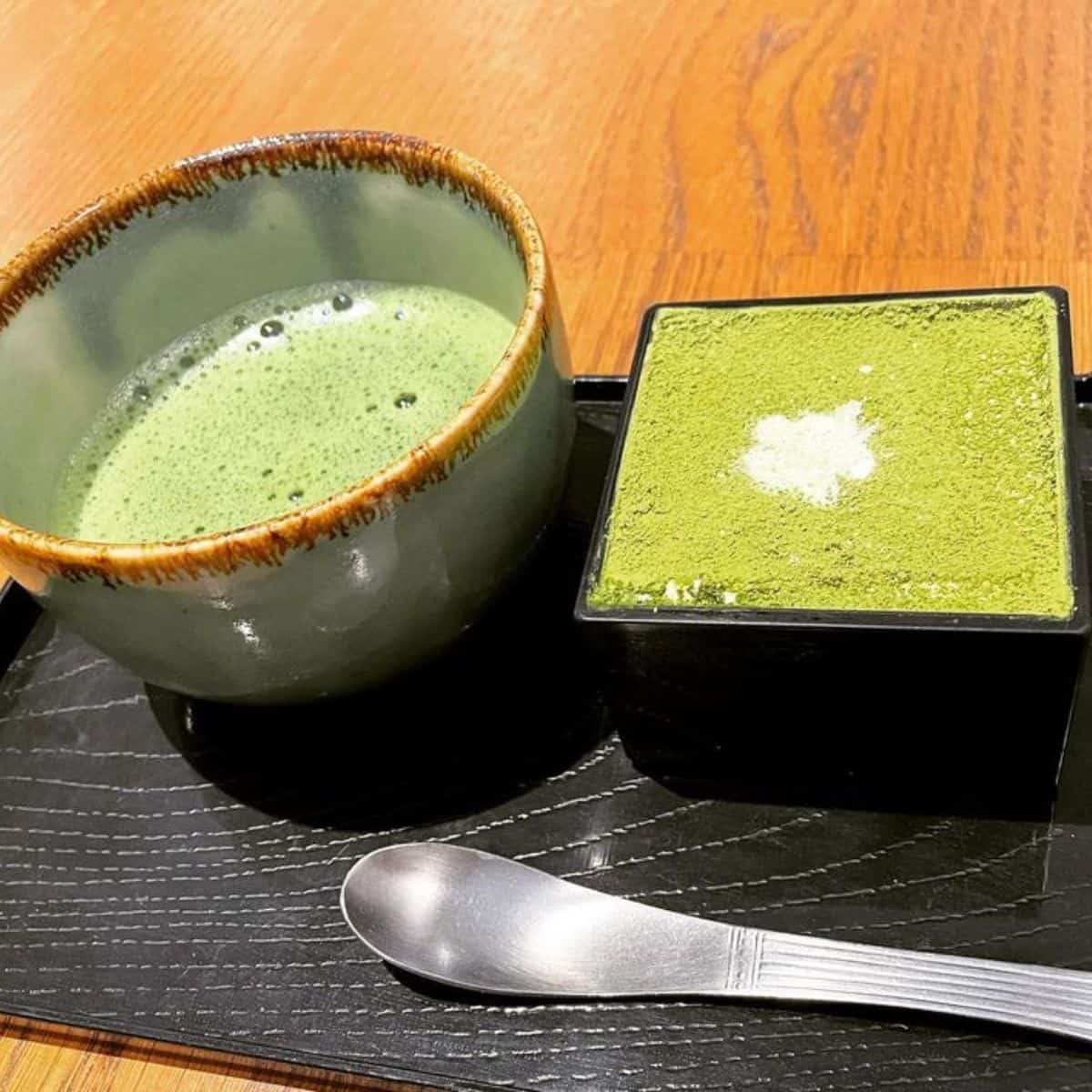 Matcha Tiramisu in a black square shape glassware paired with a matcha tea
