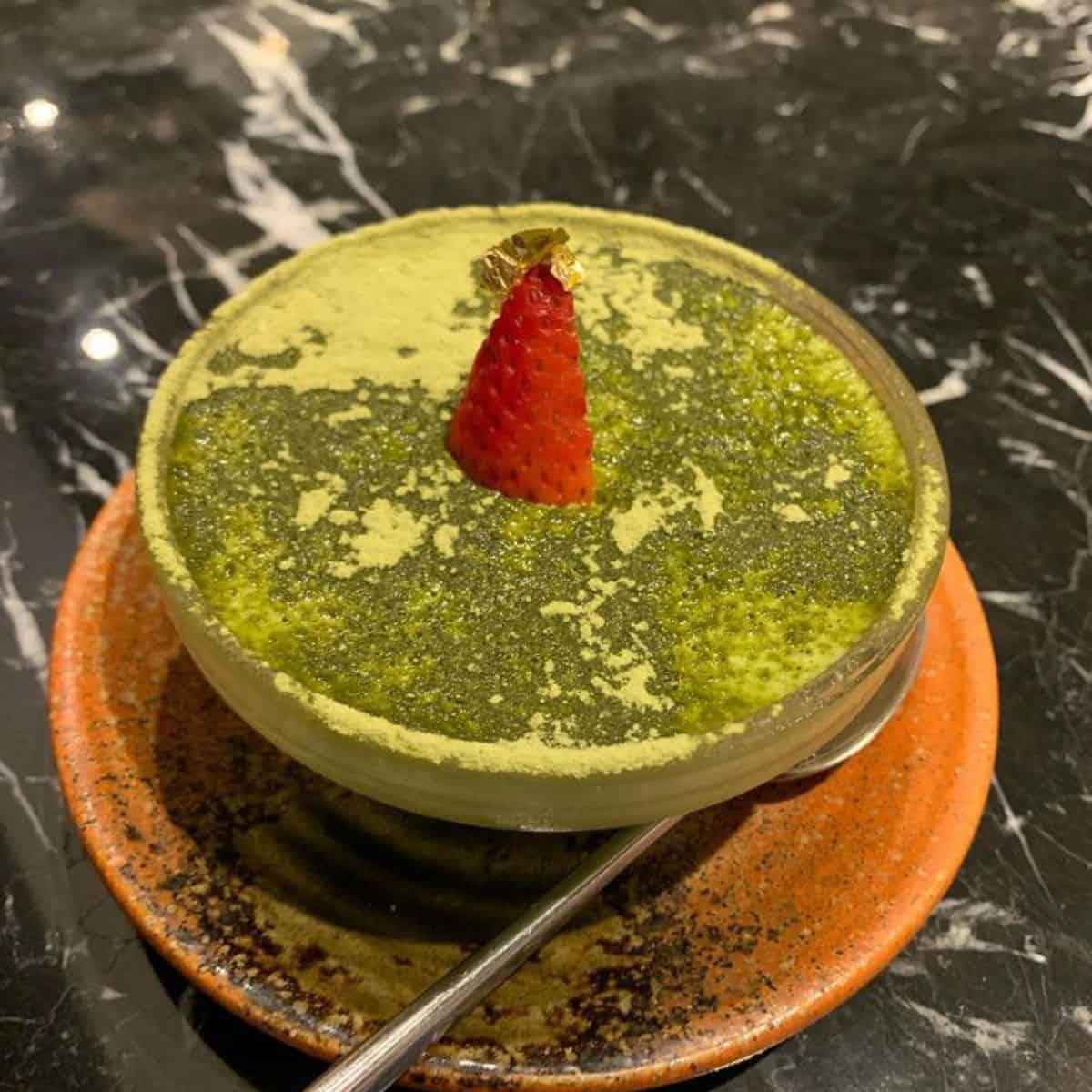 Matcha Tiramisu in a small bowl with a sliced strawberry on top