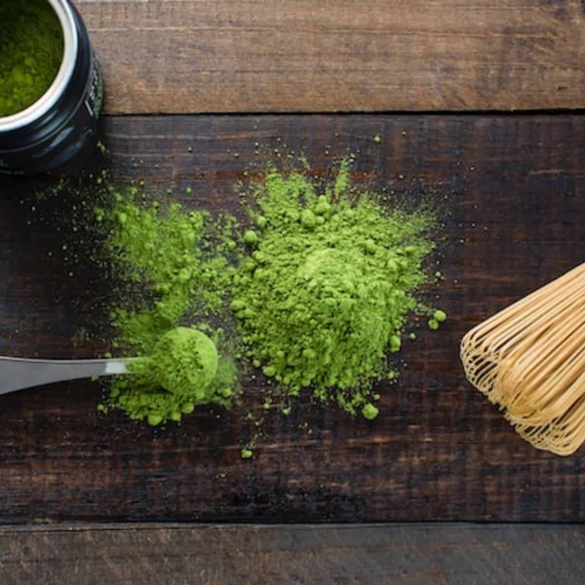 Matcha powder spreading in a spoon and woody table