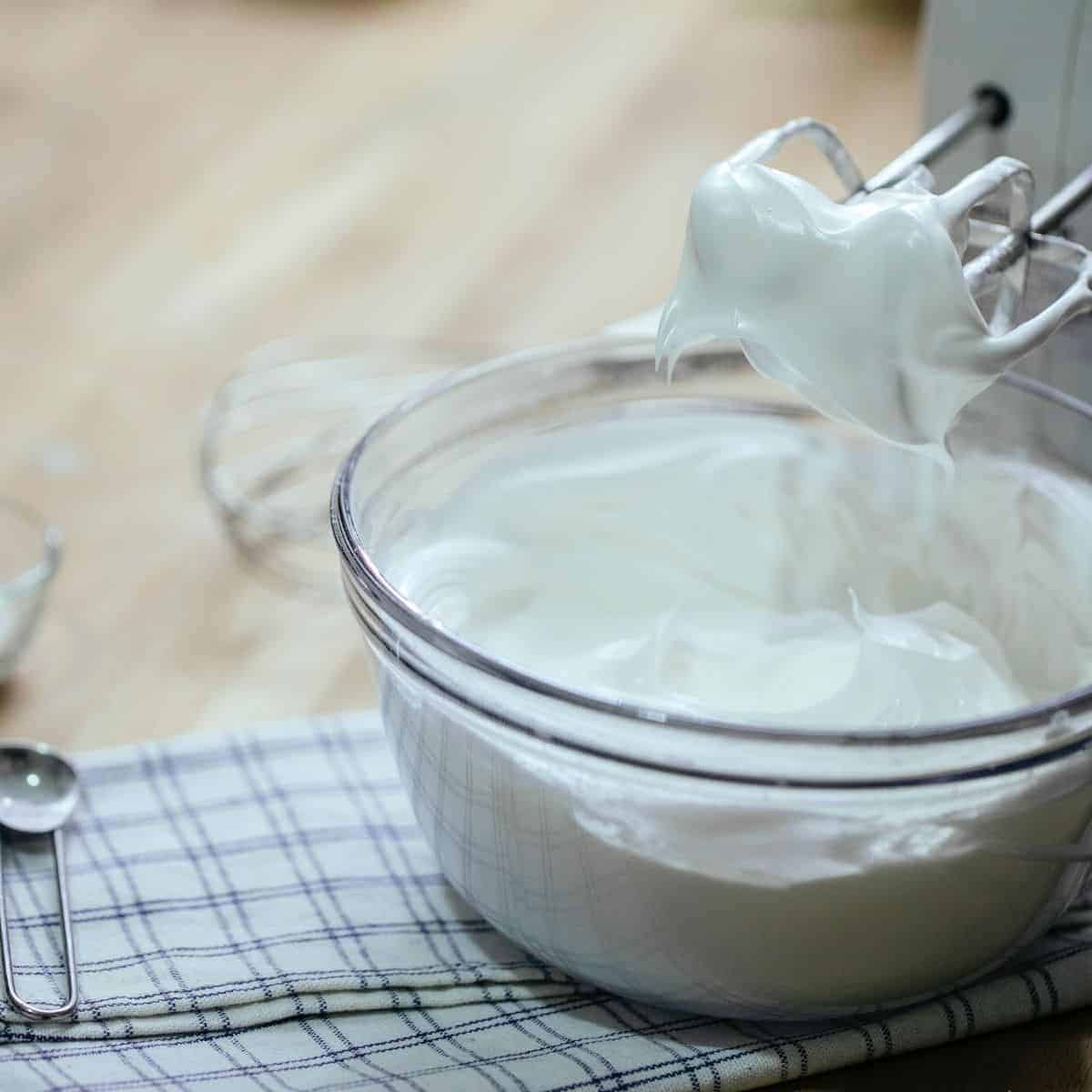 Whipped cream in a glass bowl and mixer