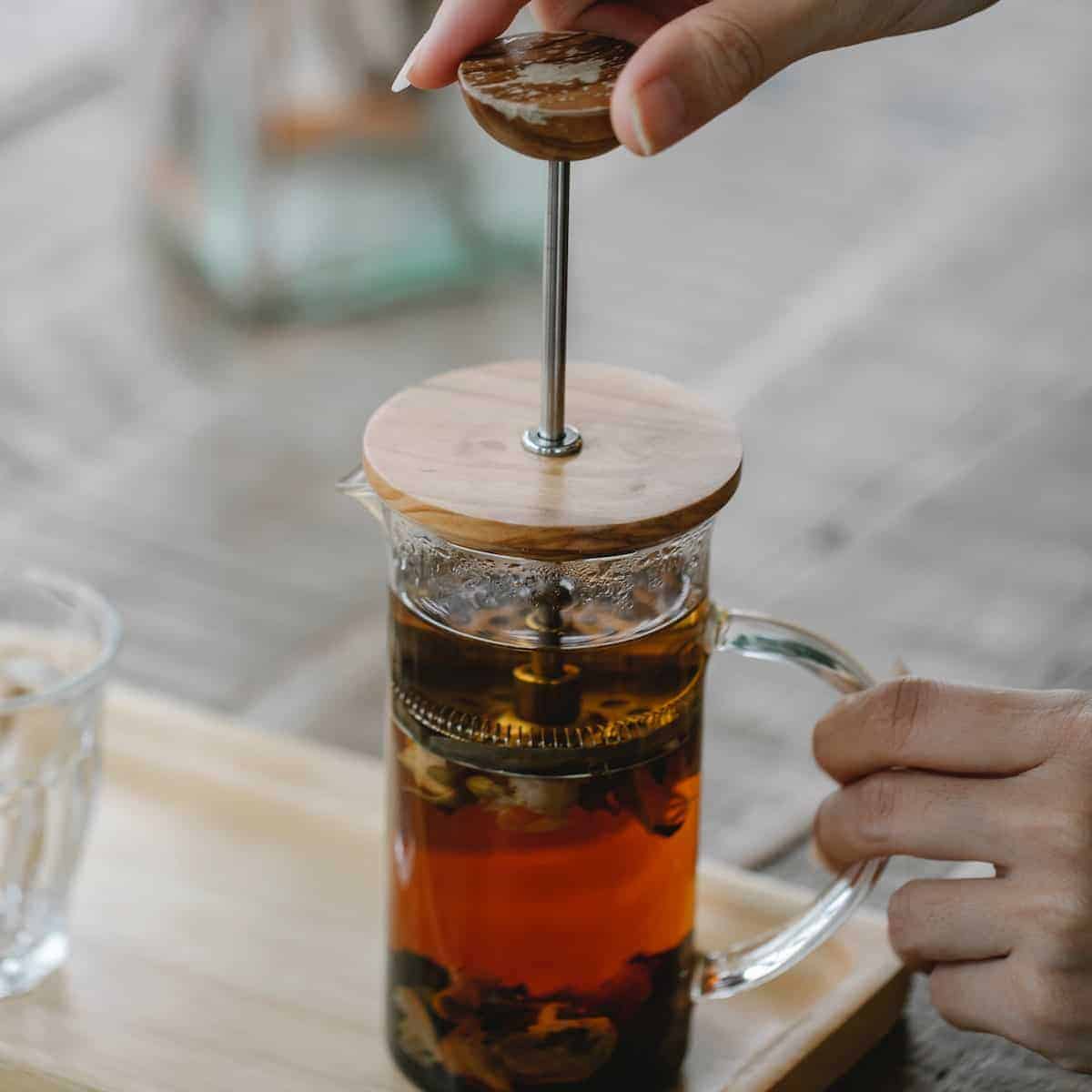 A woman using a press plunger to extract tea leaves