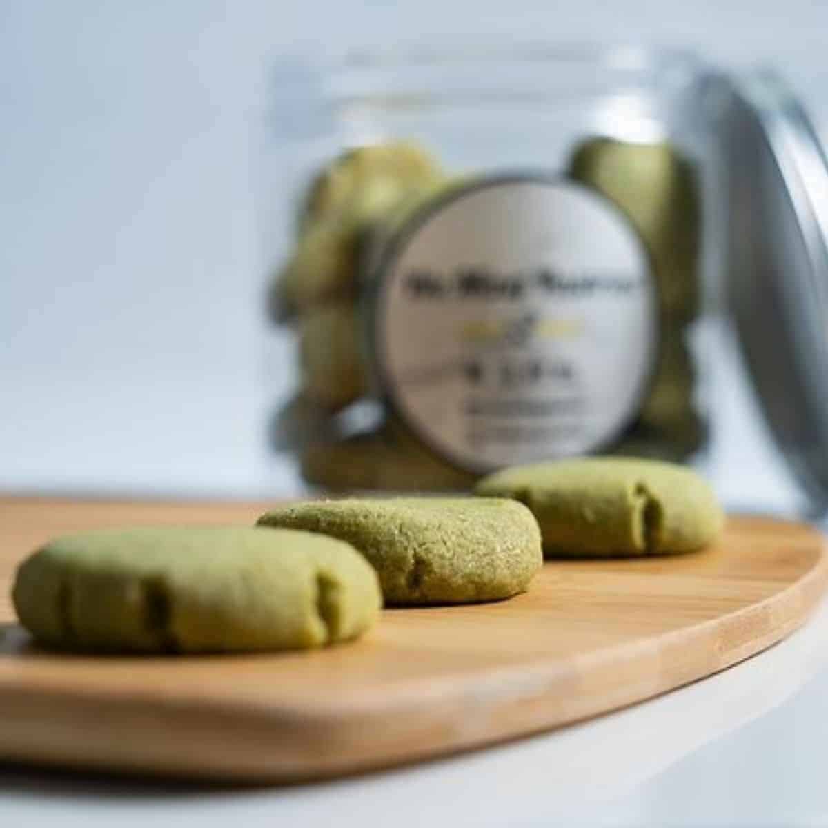 Three beautiful pieces of green tea  snacks placed in a wood chopping board