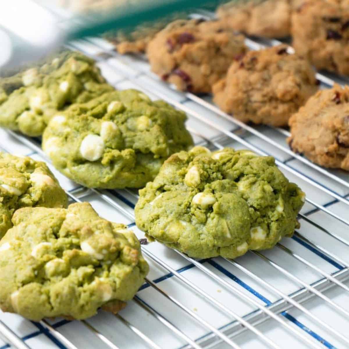 Two groups of green and brown coloured cookies line up in an oven tray