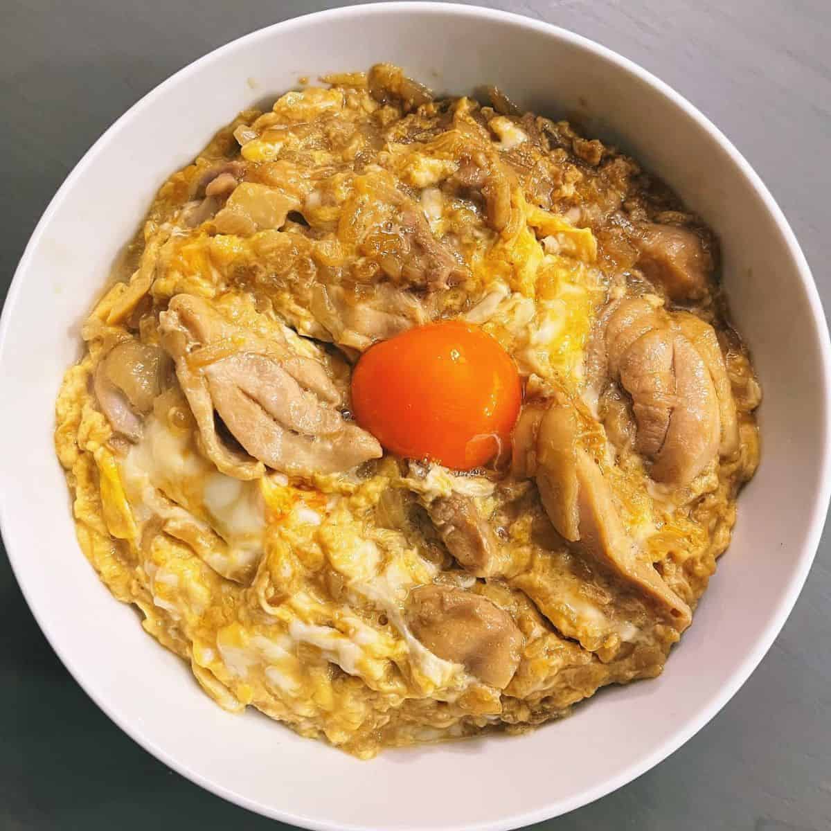 Beautifully prepared Oyakodon in a white bowl with egg yolk in the middle
