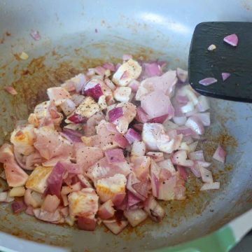 Adding diced chicken and onion to a pan