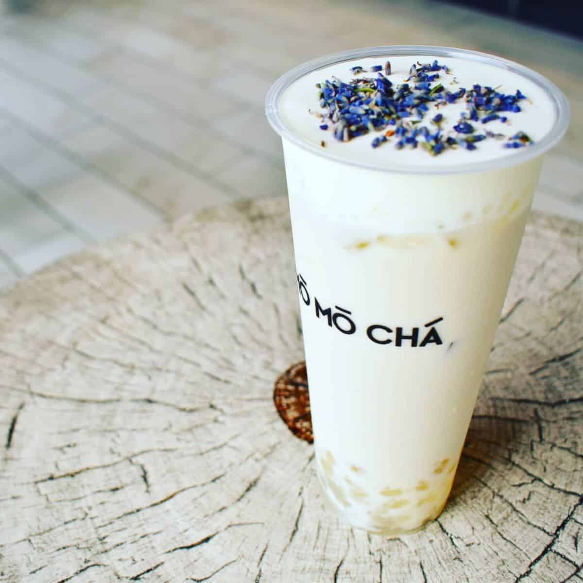 A full glass of Lavender Milk Tea from MoMoCha with transparent boba pearls