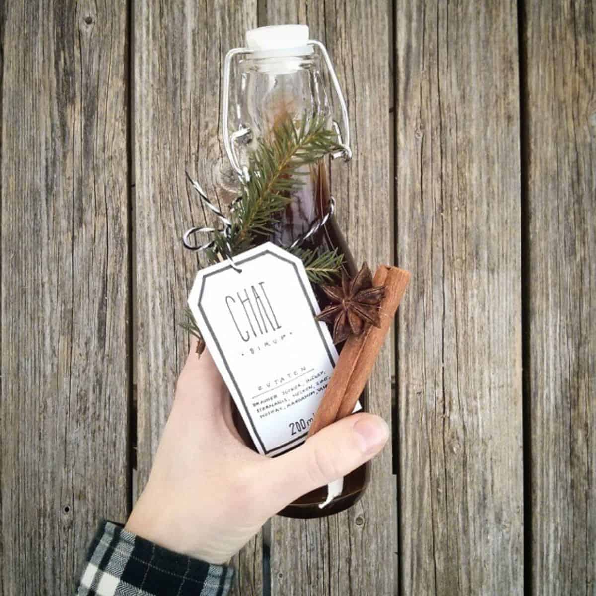  A hand holding a cute bottle of homemade Chai syrup with a pretty tag and decor