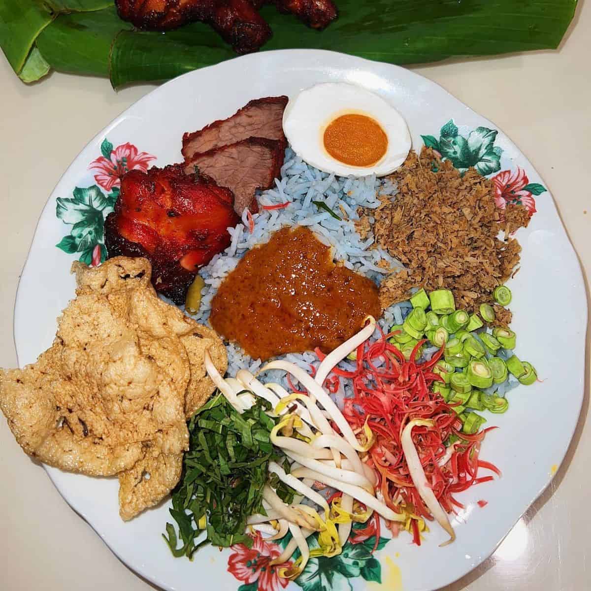 Nasi Kerabu in a flowery white plate with one slice of salted egg