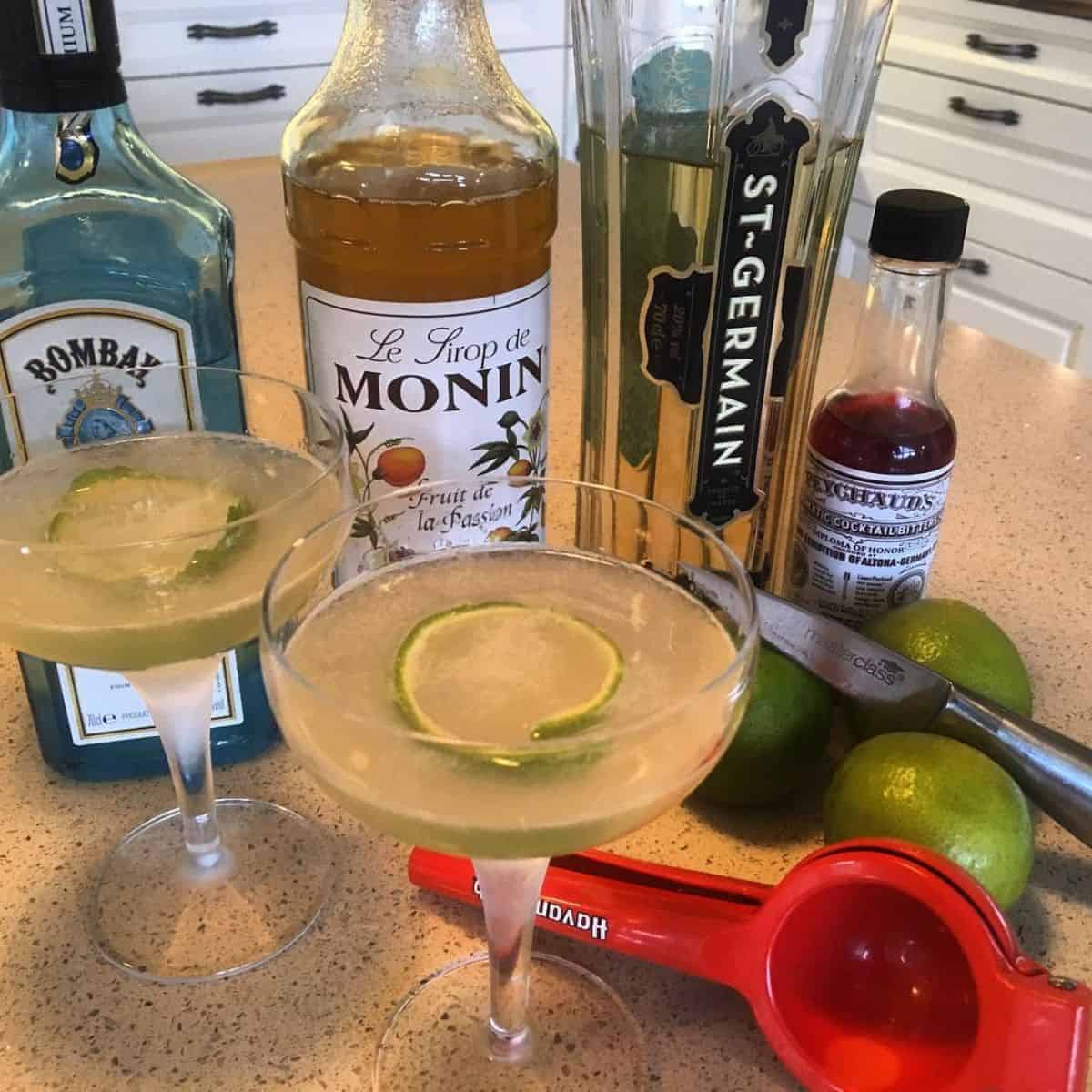 Fancy cocktail glasses with its ingredients around the table including Monin Passion Fruit Syrup