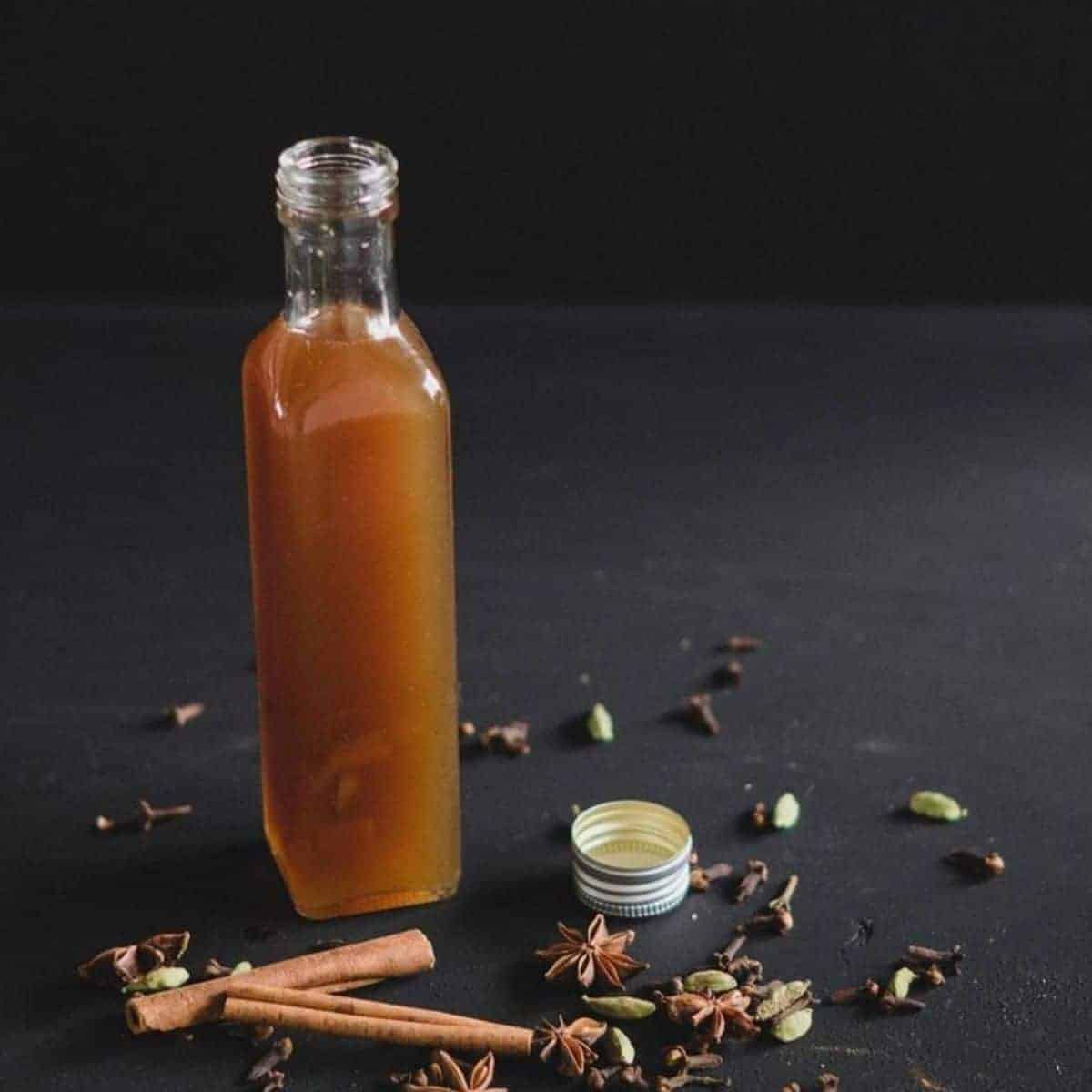 Spices messing up the table and a long transparent bottle filled with brownish liquid