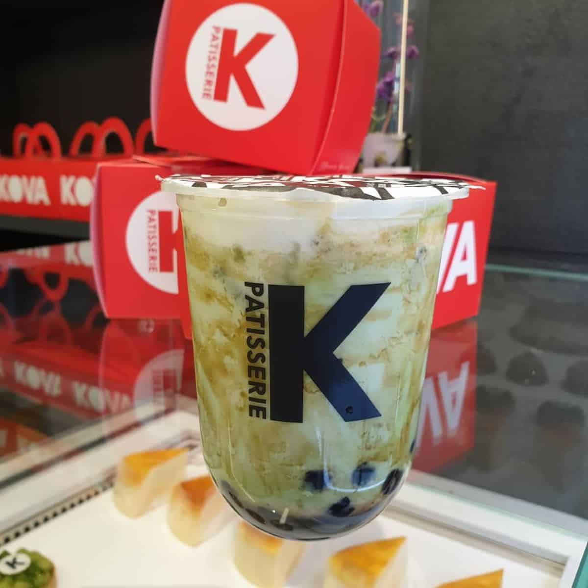 A luscious cup of a boba drink with red boxes in the background