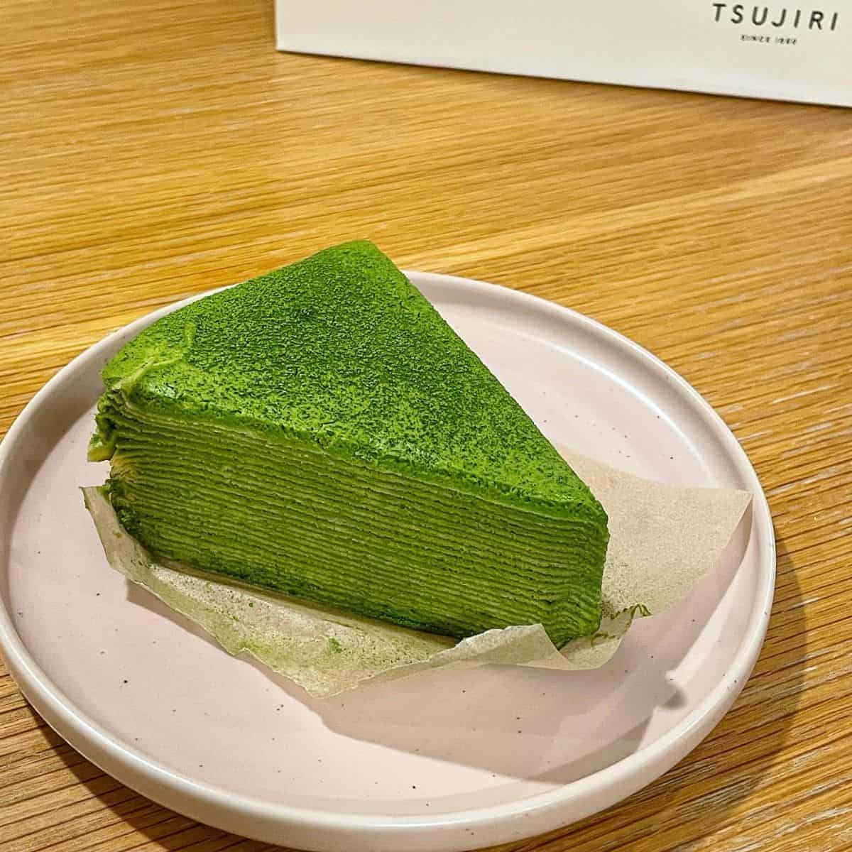 A delectable slice of Matcha Crepe Cake with beautiful green hue placed in a white ceramic plate