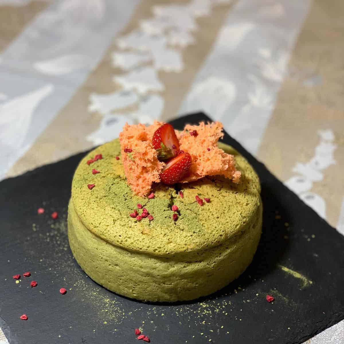 A small serving of matcha cheesecake with pink garnishes