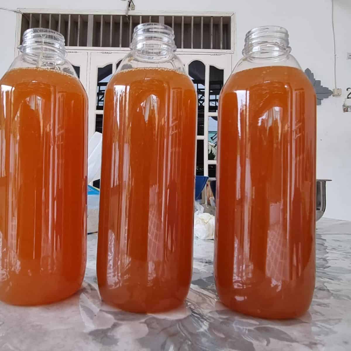 Three bottles containing dark orange liquid