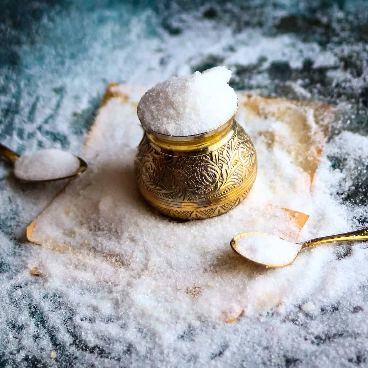 White sugar in a golden container to be used for a passion fruit recipe with two golden spoons on each side