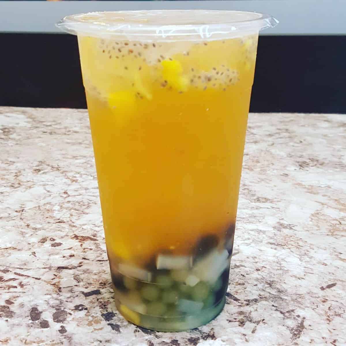 Cold boba drink with lychee, mango bits, passion fruit, and jelly.