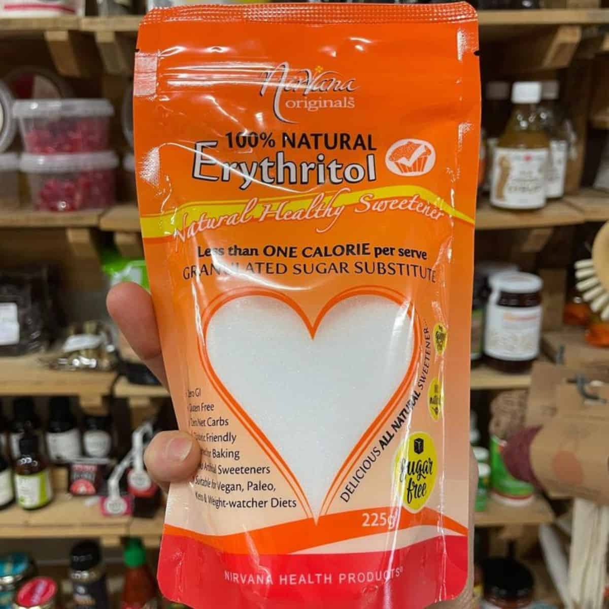 A hand holding erythritol in an orange packaging