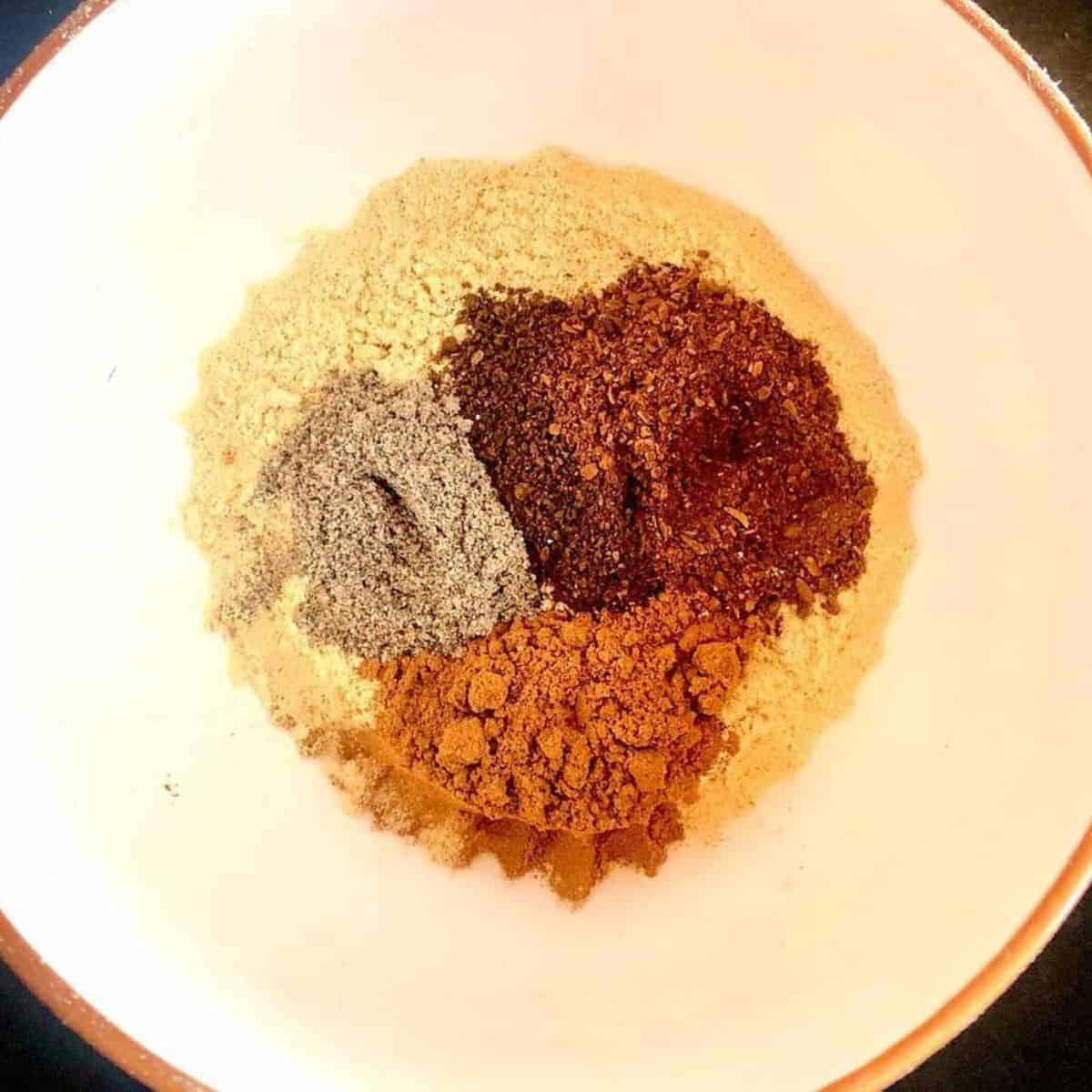 Orangey and brownish spices mixed in a white bowl