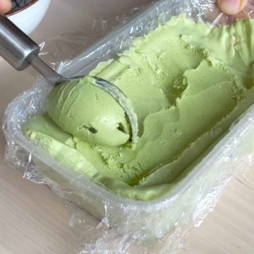 scooping matcha ice cream out of tub