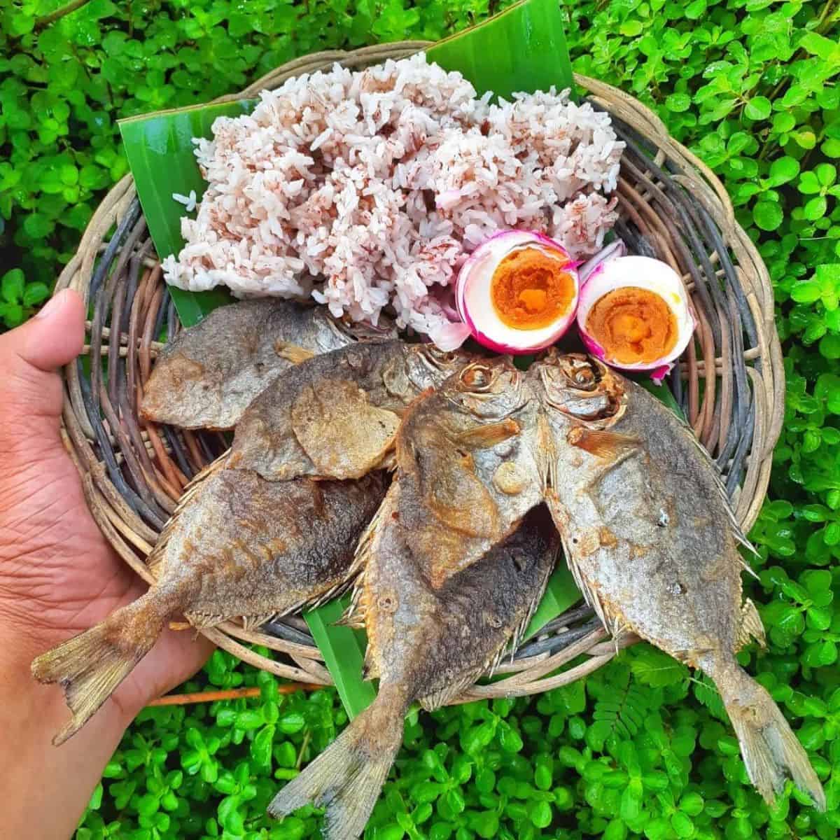 Mouthwatering breakfast plate with fried fish, red rice, and salted egg